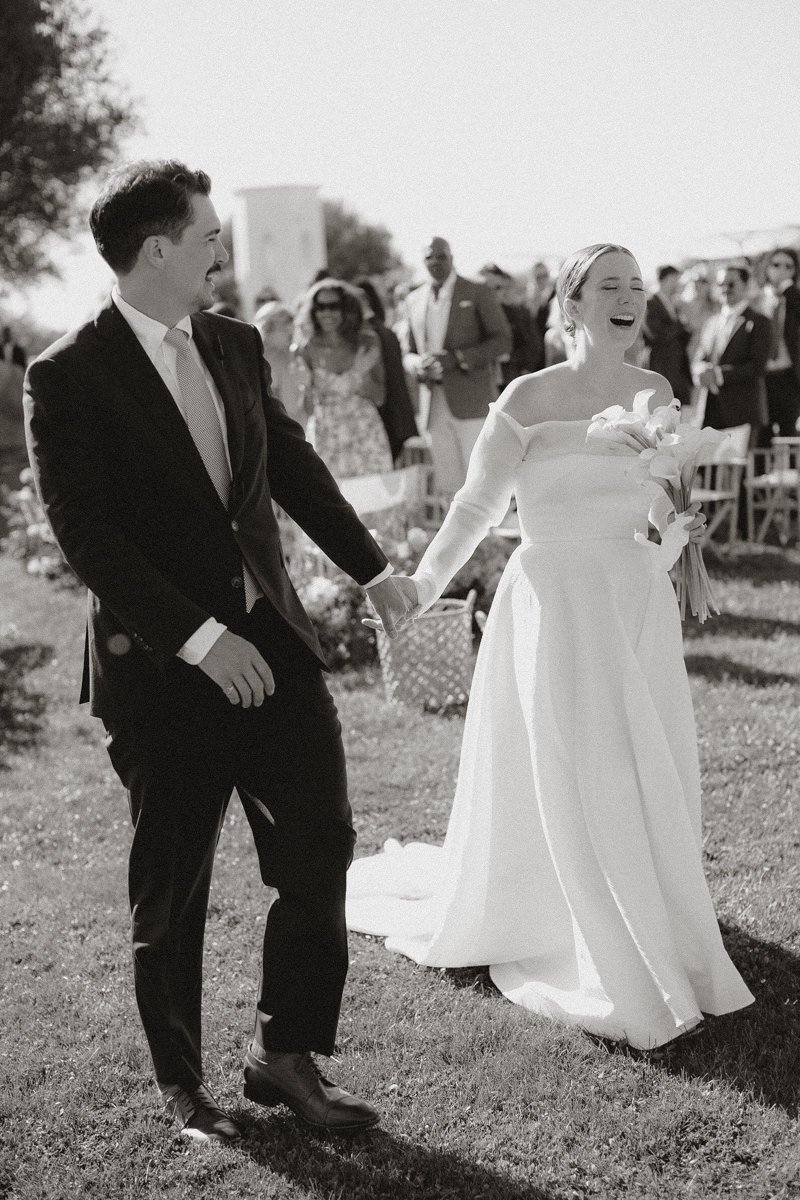 Happy bride and groom walking out of the ceremony smiling during their destination wedding at São Lourenço do Barrocal in the Alentejo countryside, captured by Arte Magna wedding photographer